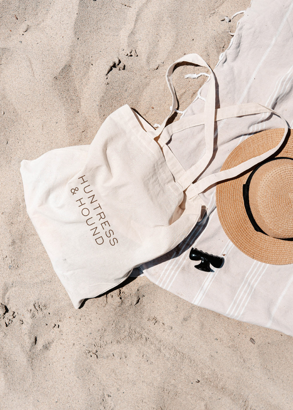 Tote bag on the beach with Huntress and Hound logo