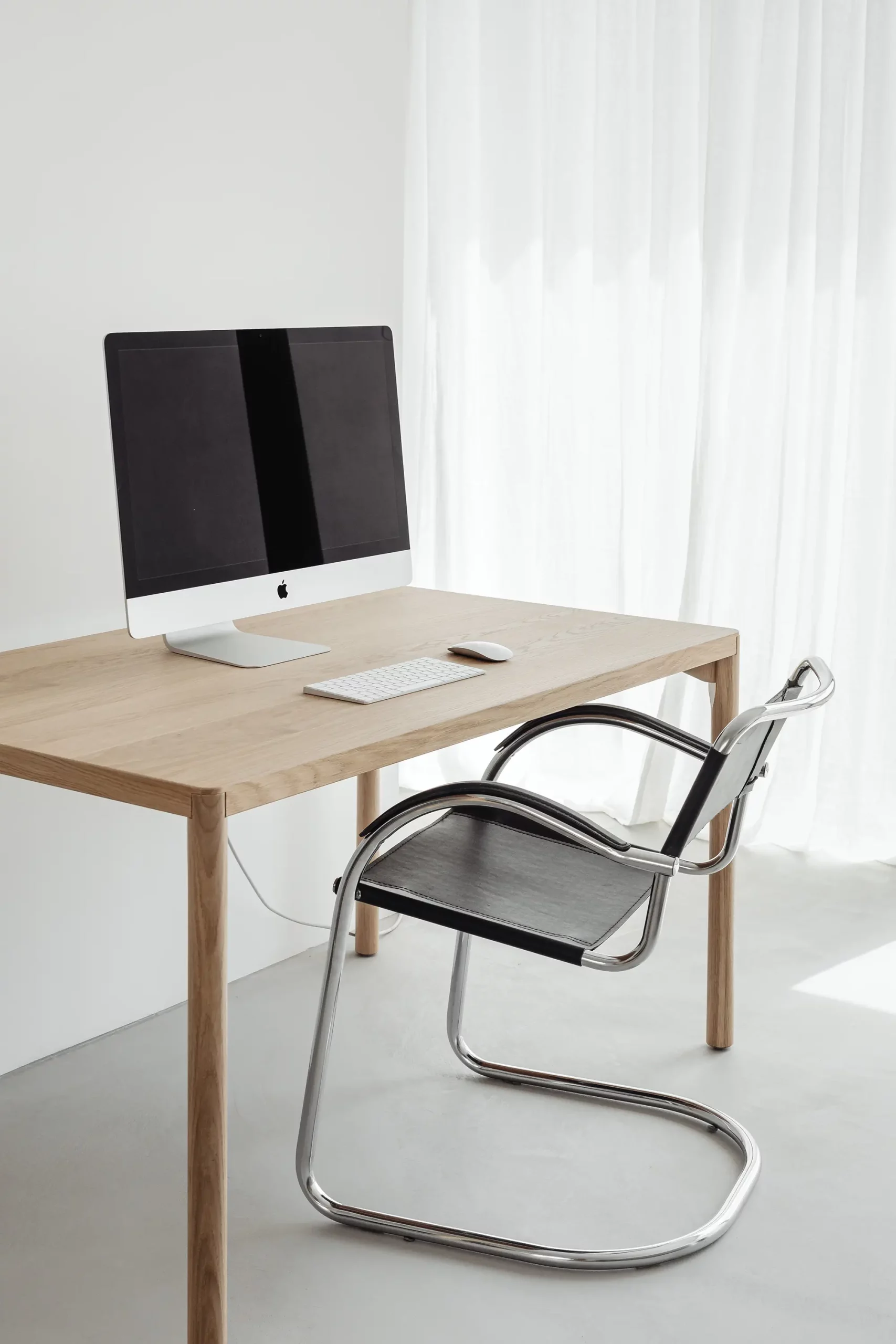 Computer at a timber desk with black desk chair