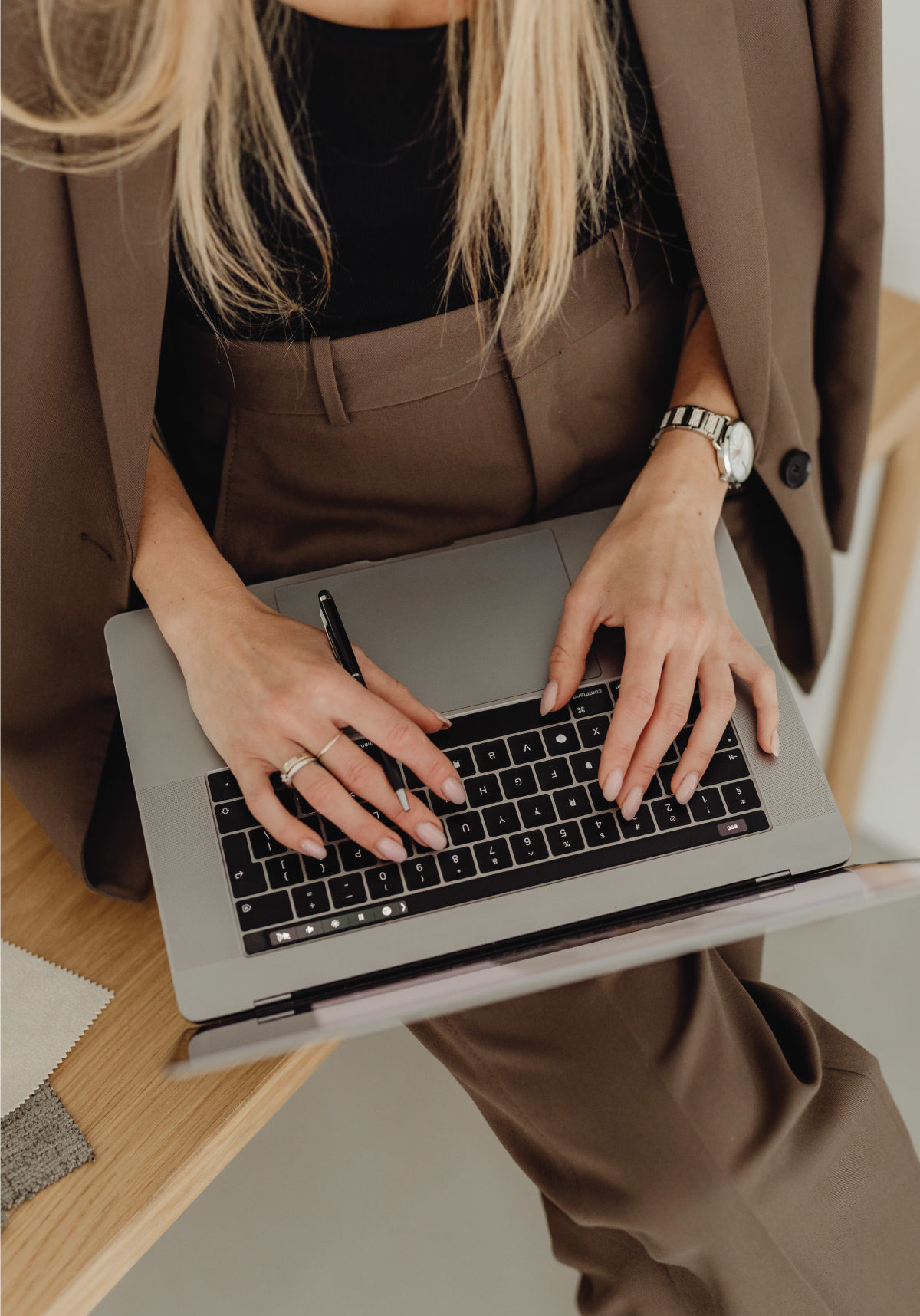 Woman is brown and black business attire sitting down typing at a laptop keyboard